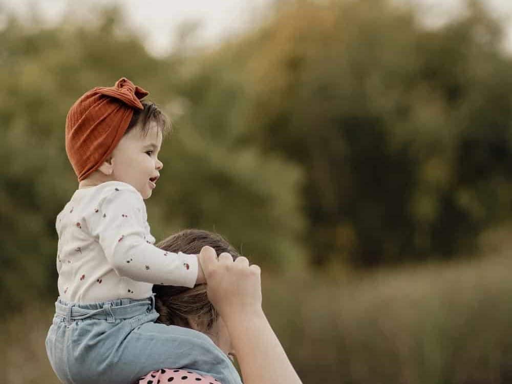 Toddler sitting on mothers shoulders